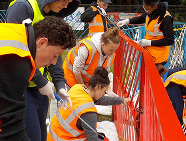 Students in h vis jackets painting a muriel